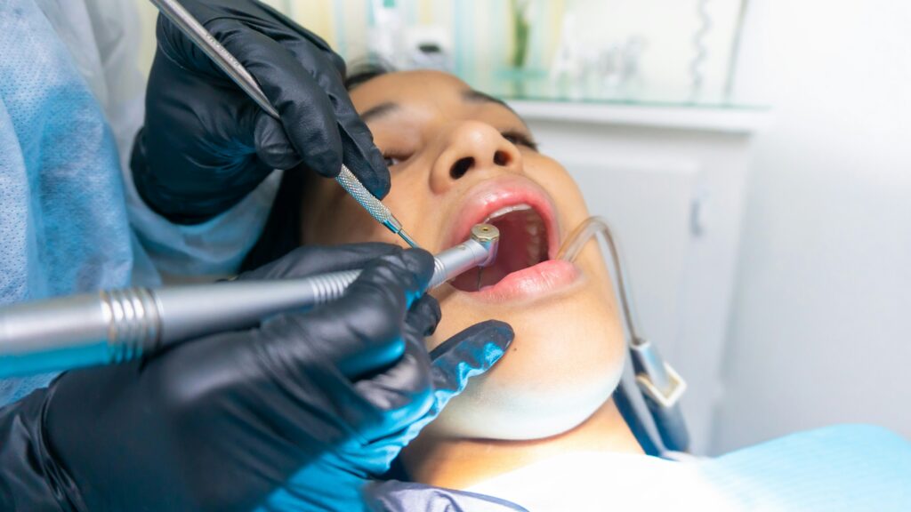 A close-up of a woman undergoing a tooth extraction procedure at a dental clinic.